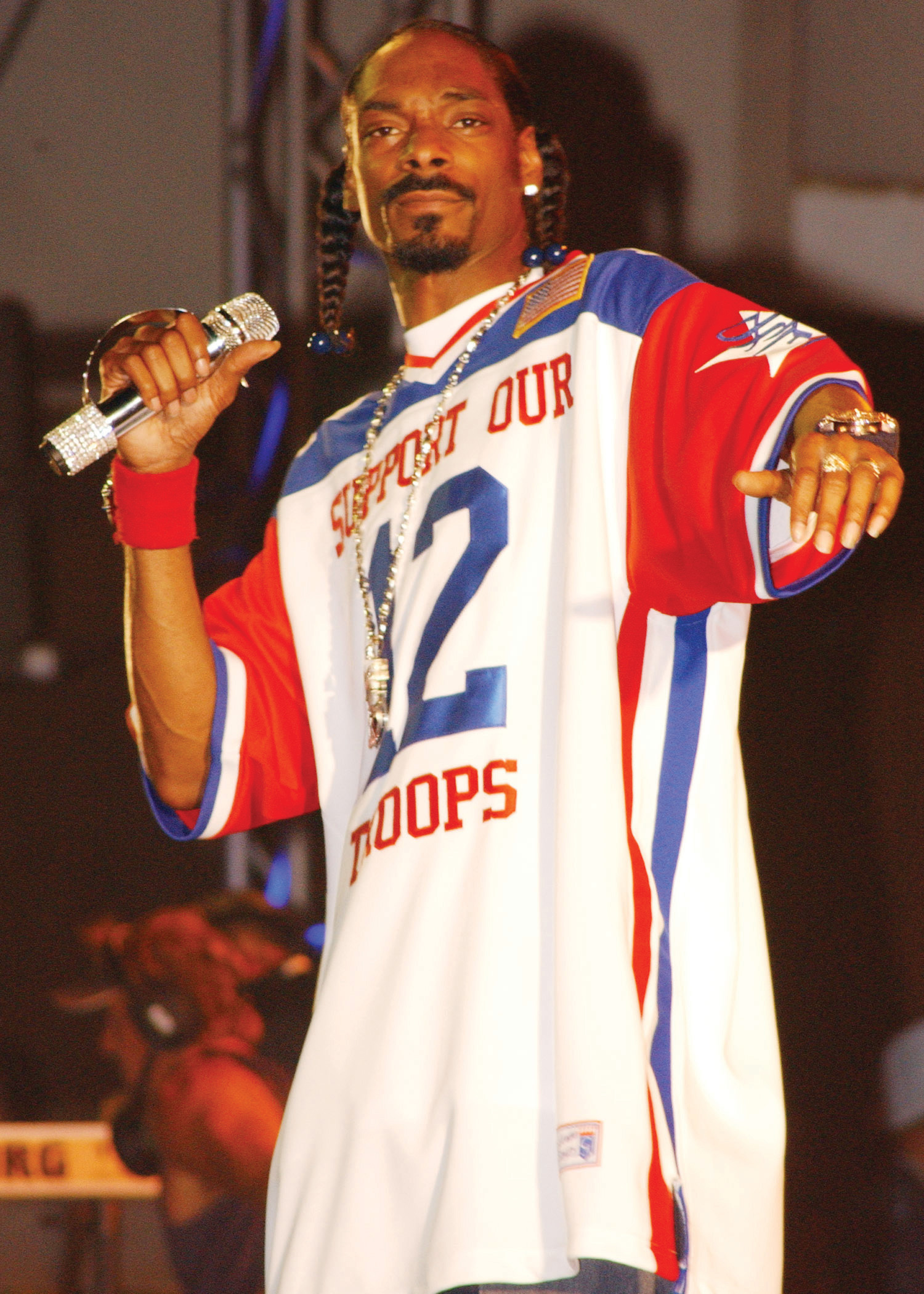 Photo of Snoop Dogg wearing a red, white, and blue basketball shirt that reads, "Support Our Troops."