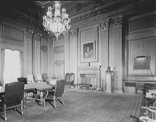 Black-and-white photo of the Supreme Court conference room. Room has a chandelier, a long table, and a fireplace.